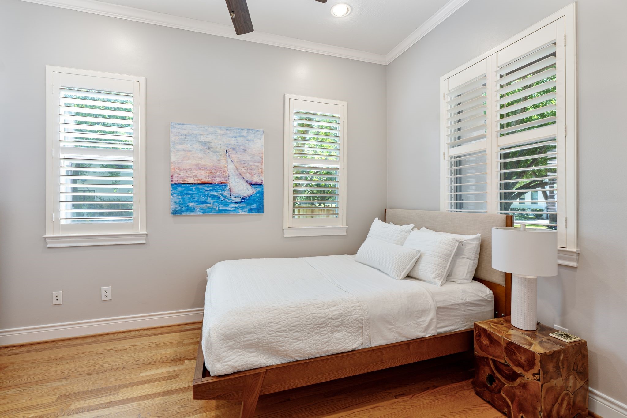 3822 Merrick Street Houston, TX 77025 - Photo 15 of 34 This bright and airy ground-floor bedroom offers hardwood floors, crown molding, recessed lighting, and plantation shutters across three windows — filling the space with natural light from multiple angles.