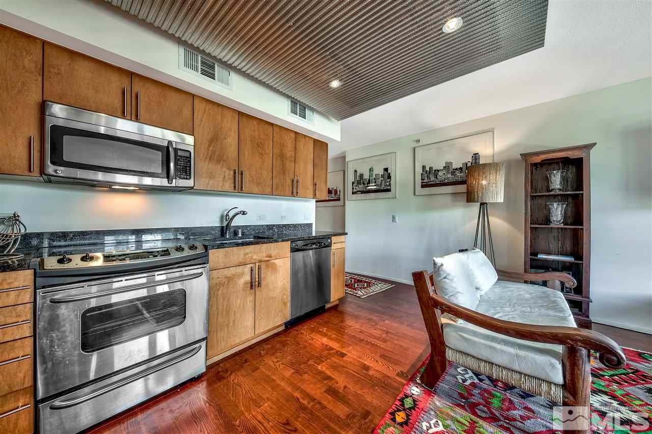 255 North Sierra Street Reno, NV 89501 - Photo 5 of 17 a kitchen with stainless steel appliances kitchen island granite countertop a stove top oven a sink a dining table and chairs with wooden floor