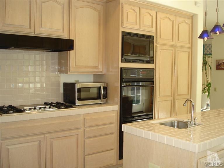 4220 Kingsview Road Moorpark, CA 93021 - Photo 22 of 54 a kitchen with granite countertop white cabinets and black appliances
