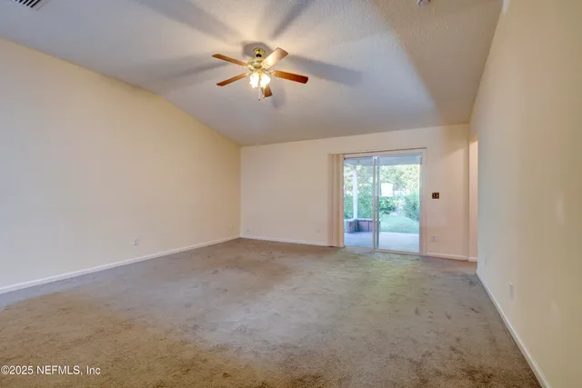an empty room with chandelier fan and windows