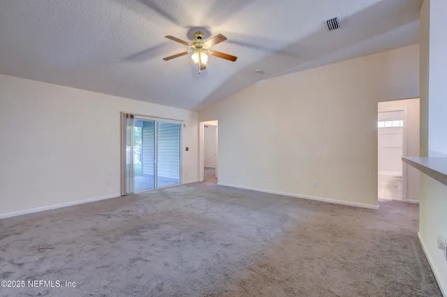 a view of an empty room with a chandelier fan