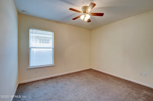 an empty room with a window and a ceiling fan