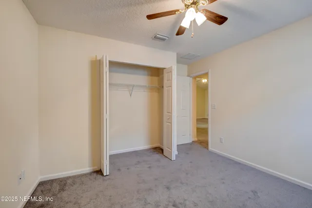 an empty room with closet and a chandelier fan