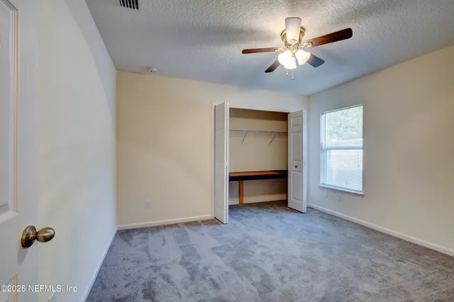 an empty room with windows and ceiling fan