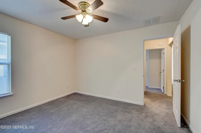 an empty room with a chandelier fan and windows