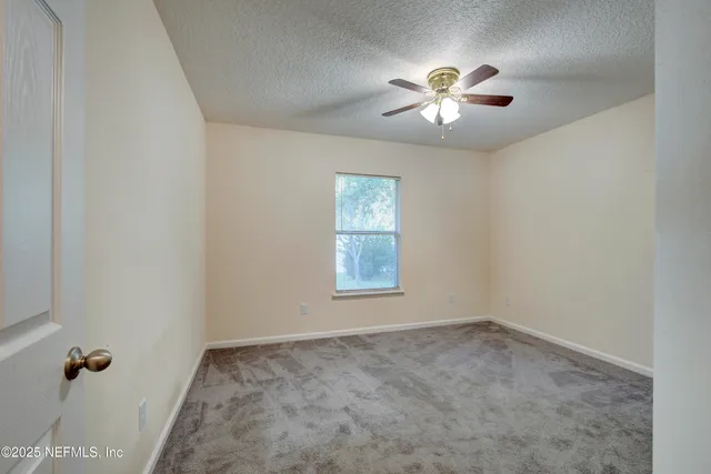 an empty room with windows and fan