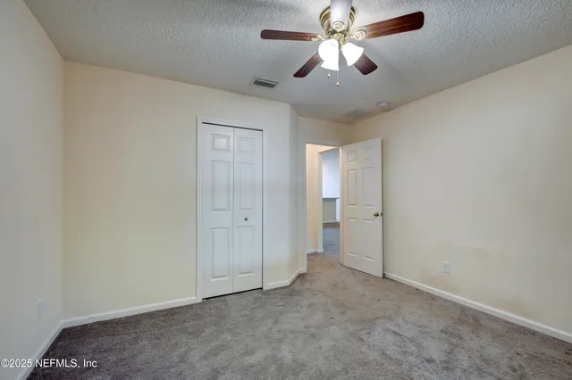 an empty room with closet and a chandelier fan