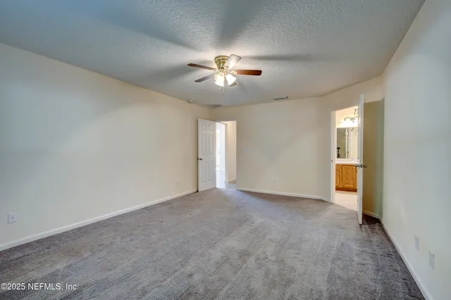 a view of an empty room and chandelier fan