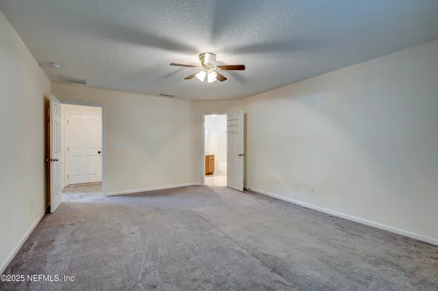 an empty room with chandelier fan and windows
