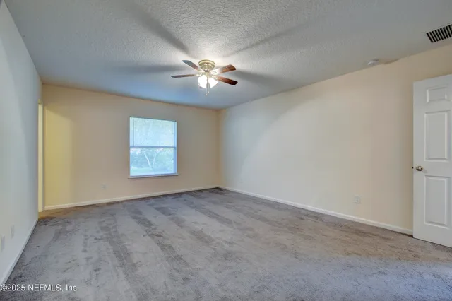 an empty room with windows and fan