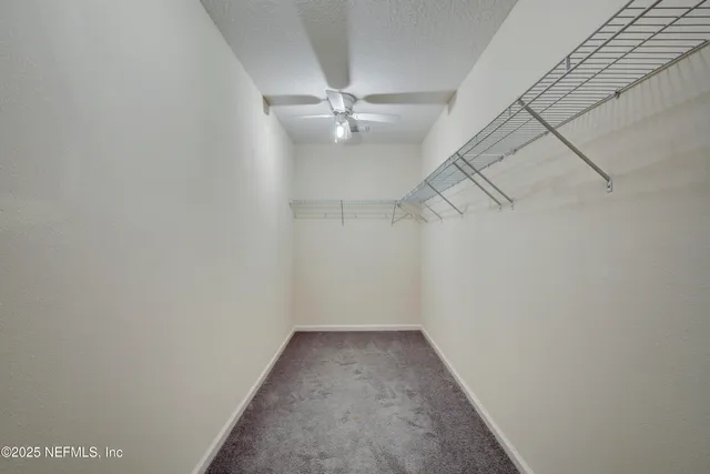 an empty room with a ceiling fan and carpet