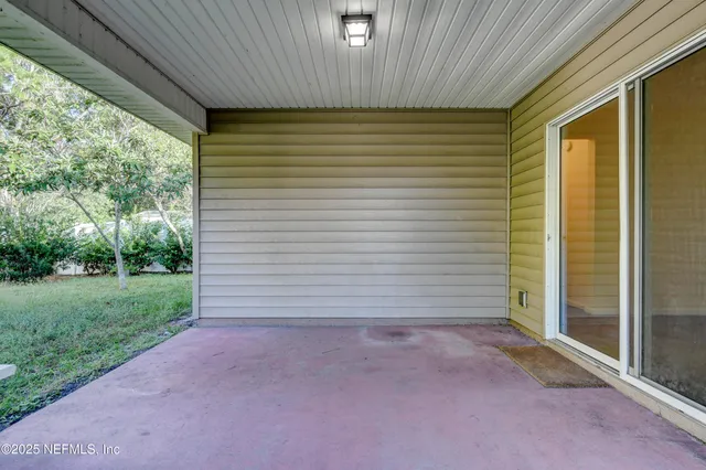 a backyard of a house with plants and large tree