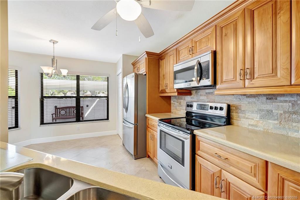6040 Southeast Martinique Drive, Unit 102 Stuart, FL 34997 - Photo 12 of 52 a kitchen with stainless steel appliances granite countertop a stove a sink and a microwave
