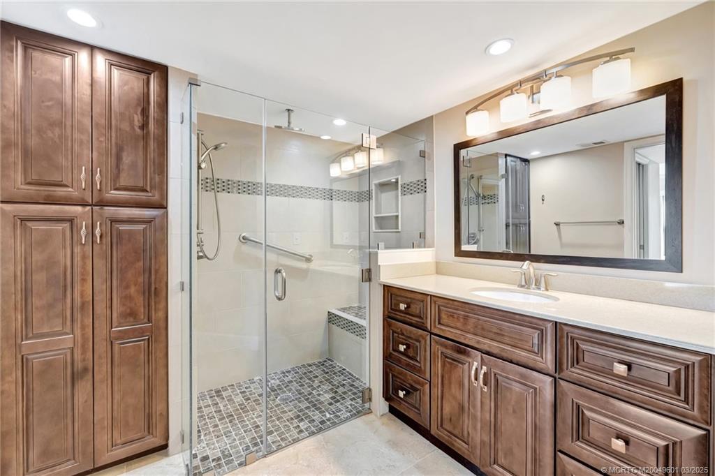 6040 Southeast Martinique Drive, Unit 102 Stuart, FL 34997 - Photo 29 of 52 a spacious bathroom with a shower sink and mirror