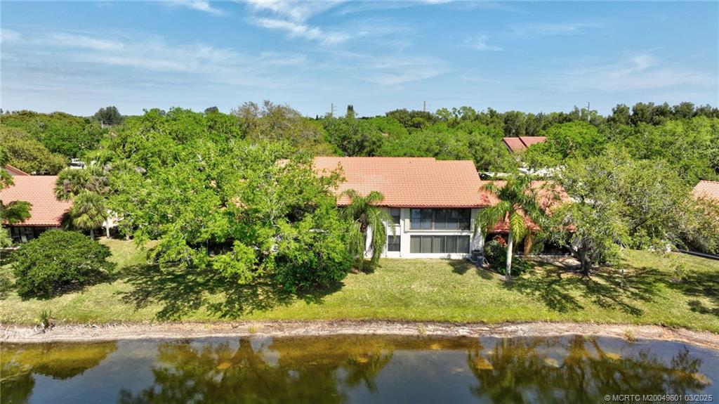 6040 Southeast Martinique Drive, Unit 102 Stuart, FL 34997 - Photo 49 of 52 a view of a house with a yard and a pond
