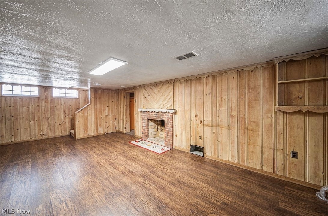 4069 Bushnell Road Cleveland, OH 44121 - Photo 27 of 39 Below grade area featuring dark wood finished floors, a brick fireplace, a textured ceiling, and wooden walls