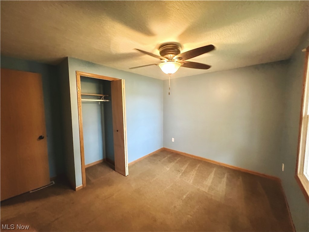 3122 Bedrock Road Northwest Dellroy, OH 44620 - Photo 20 of 23 Unfurnished bedroom featuring a closet, carpet floors, ceiling fan, and a textured ceiling