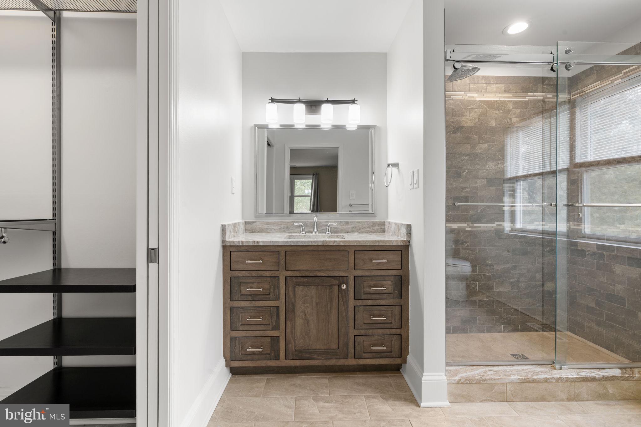 115 Roumfort Road, Unit 26 Philadelphia, PA 19119 - Photo 20 of 33 a bathroom with a granite countertop sink a mirror and a shower
