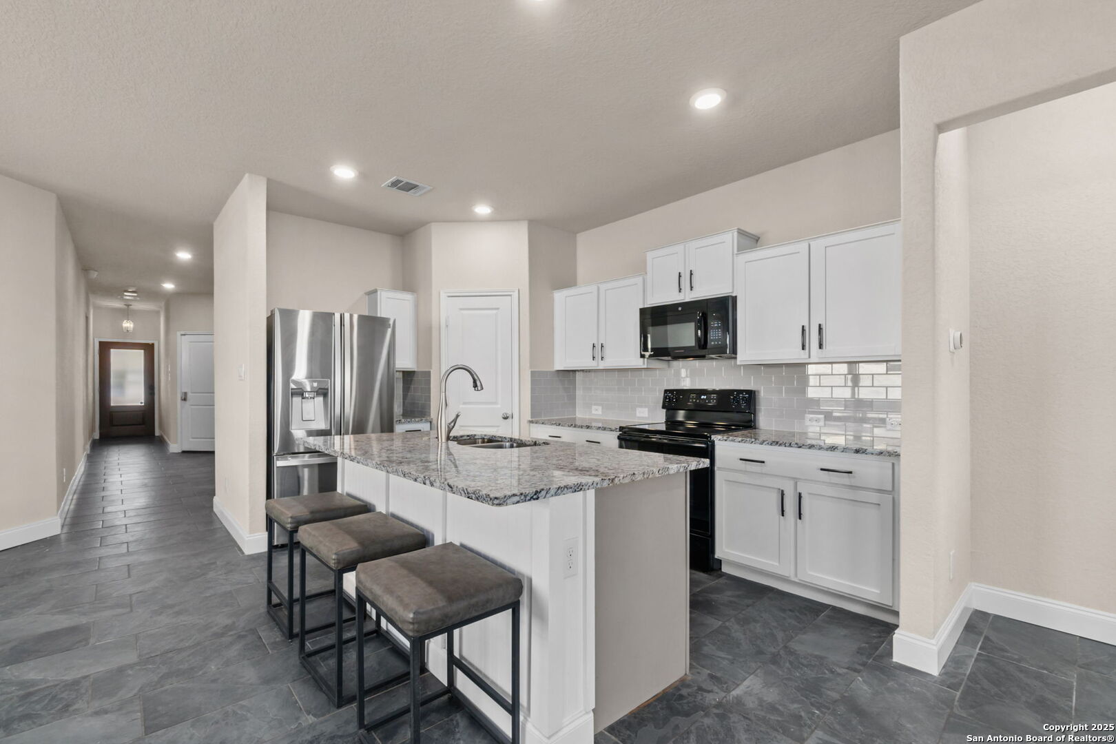 10306 Midsummer Meadow Converse, TX 78109 - Photo 11 of 20 a kitchen with stainless steel appliances kitchen island granite countertop a stove top oven a sink dishwasher a refrigerator and white cabinets with wooden floor