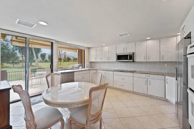 a kitchen with stainless steel appliances granite countertop a stove a sink dishwasher a dining table and chairs with wooden floor