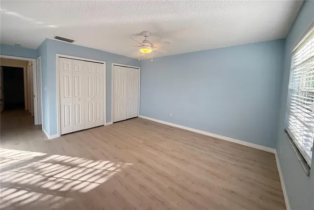 an empty room with windows and chandelier fan