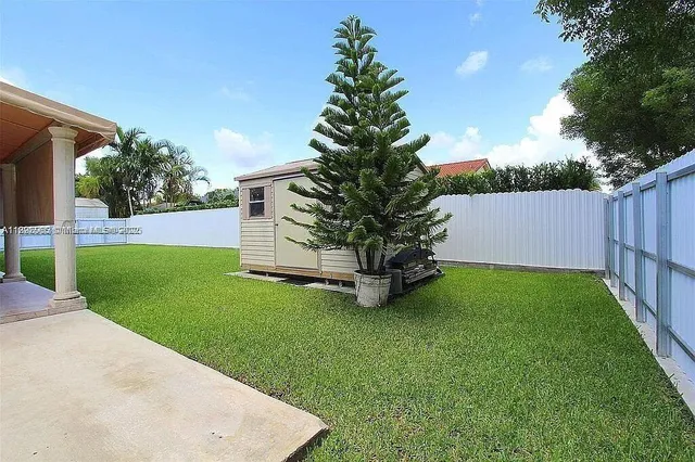a backyard of a house with plants and large tree