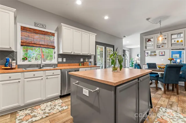 a kitchen with kitchen island granite countertop a table chairs sink and cabinets
