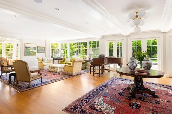 a living room with furniture large windows and wooden floor