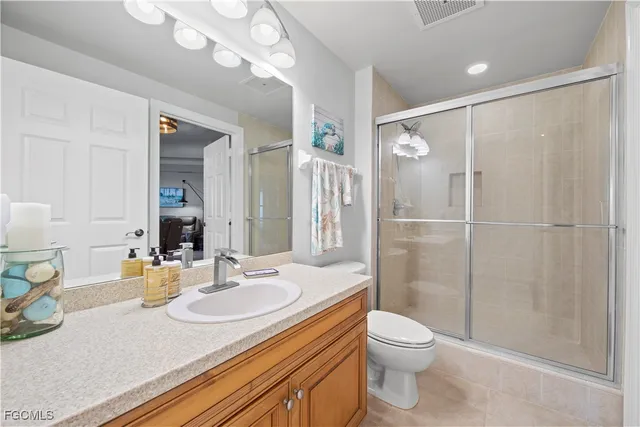 a bathroom with a granite countertop sink a toilet a mirror and shower