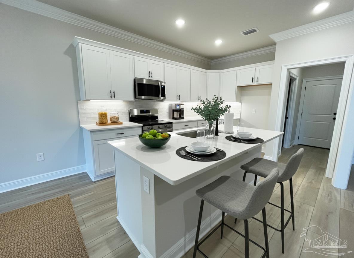 7950 Klondike Road, Unit 25 Pensacola, FL 32526 - Photo 3 of 6 a kitchen with stainless steel appliances a sink a microwave refrigerator and chairs