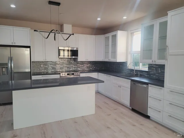 a kitchen with stainless steel appliances granite countertop a sink a stove and a refrigerator