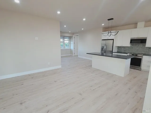 a view of a kitchen with kitchen island a sink wooden floor and a counter top space
