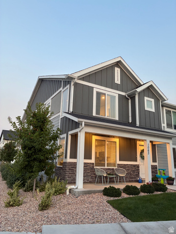 673 West 1920 South, Unit 1063 Provo, UT 84601 - Photo 2 of 15 Two-story residence featuring a covered front porch with stone accents, board and batten siding, and a well-maintained lawn with decorative gravel landscaping