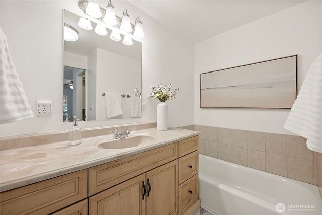 a bathroom with a sink a large mirror and a bathtub with a potted plant