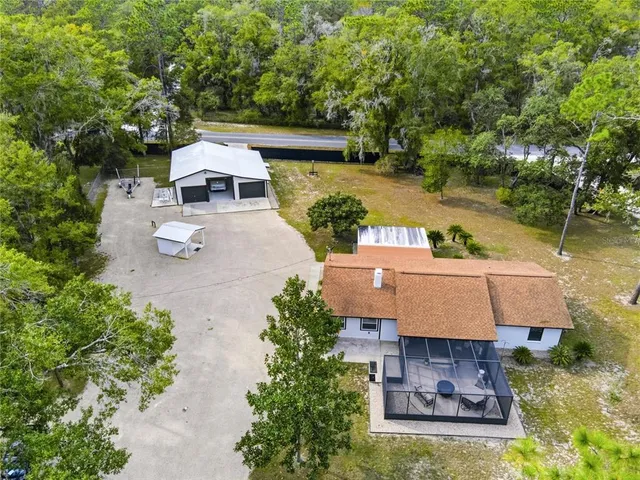 a view of a house with a yard and large trees