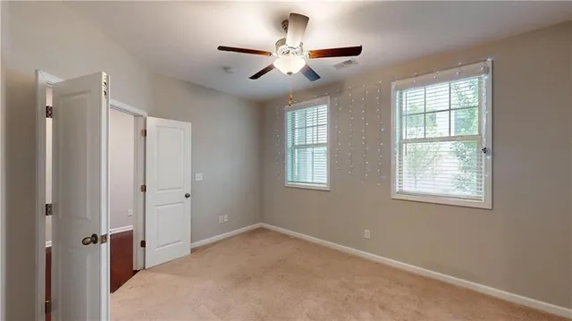 a view of a livingroom with a ceiling fan & windows