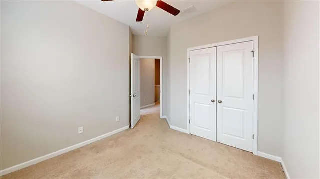 an empty room with a ceiling fan and carpet
