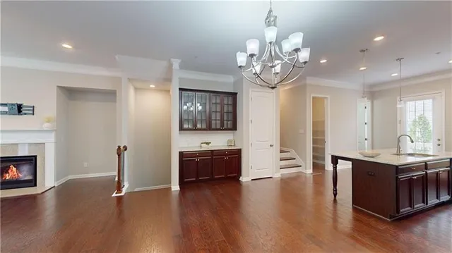 a kitchen with stainless steel appliances granite countertop a stove top oven a sink dishwasher and a fireplace with wooden floor