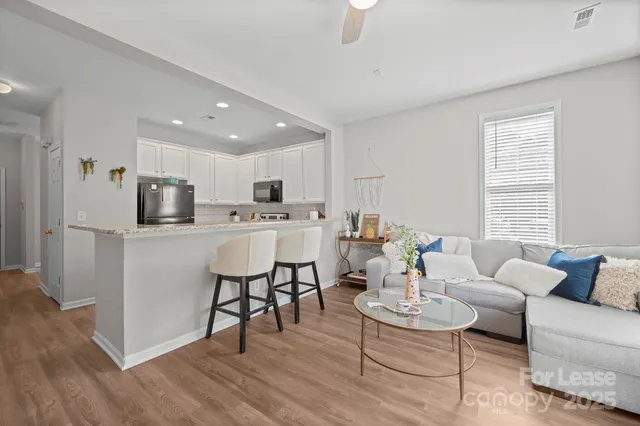 a living room with stainless steel appliances kitchen island granite countertop furniture and a wooden floor