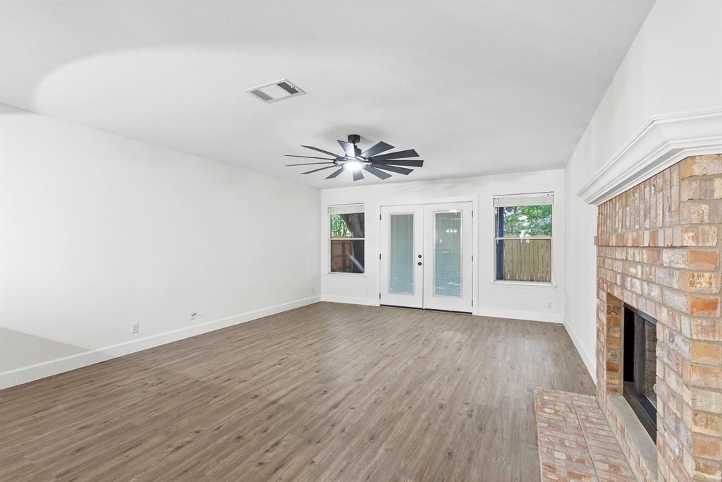 617 Barbara Way Bastrop, TX 78602 - Photo 4 of 20 A spacious room features a classic brick fireplace, modern ceiling fan, and French doors leading to the outdoors.