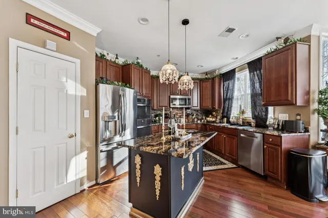 a kitchen with stainless steel appliances granite countertop a refrigerator a sink dishwasher a kitchen island with wooden cabinets and floor