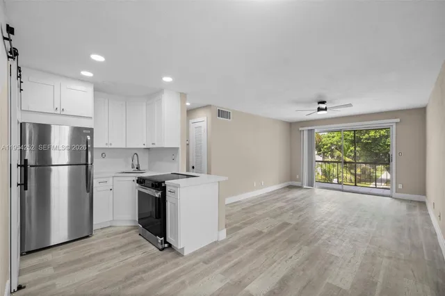 a kitchen with a refrigerator a stove top oven and wooden floors