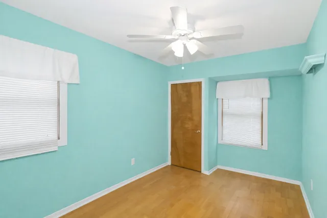 an empty room with a window and a chandelier fan