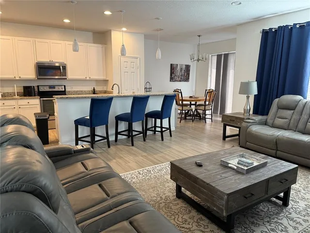 a living room with furniture a wooden floor and kitchen view