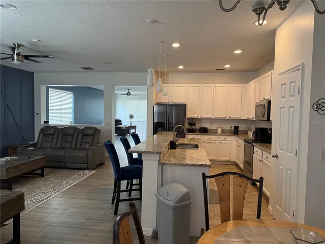 a living room with stainless steel appliances furniture a couch and a kitchen view