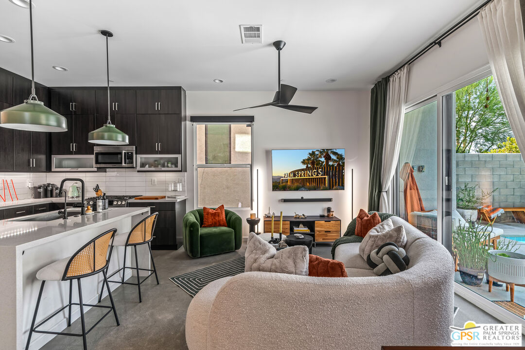 a living room with furniture kitchen view and a large window