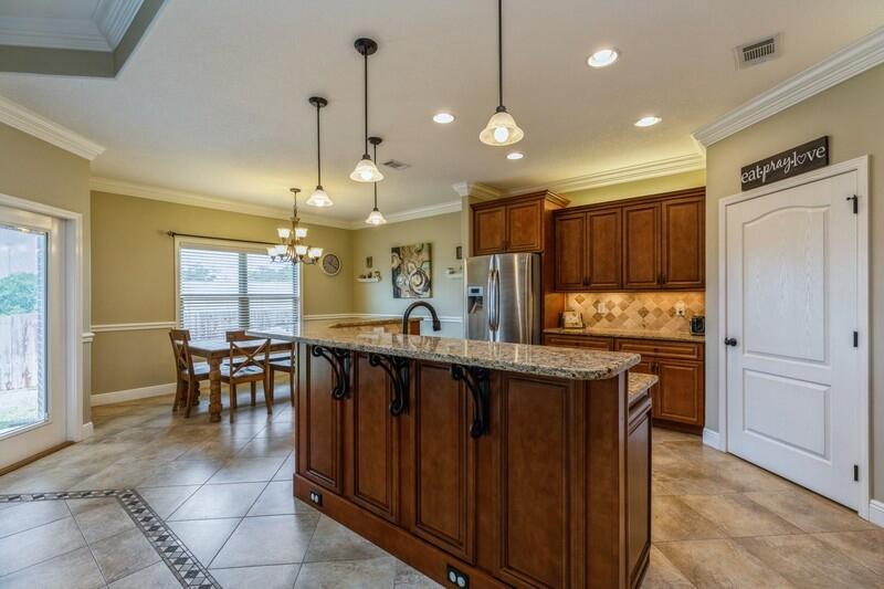 4595 Hermosa Road Crestview, FL 32539 - Photo 8 of 35 a kitchen with kitchen island a dining table chairs sink and cabinets
