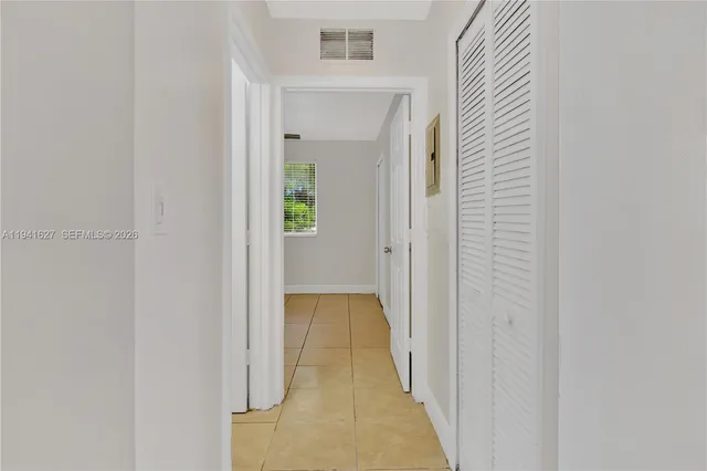 a view of a hallway with wooden floor and a bathroom