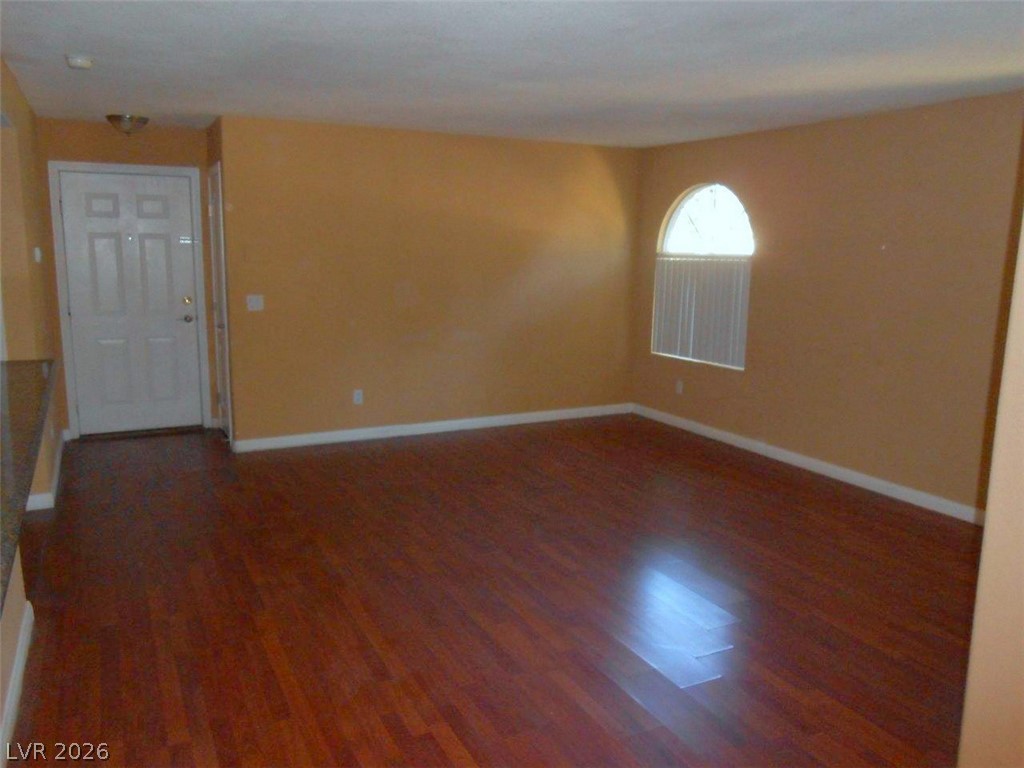 9325 West Desert Inn Road, Unit 132 Las Vegas, NV 89117 - Photo 12 of 36 Rich hardwood floors span this open-concept living space, illuminated by an elegant arched window.