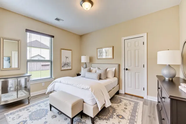 a bedroom with a bed wooden floor and a lamp on dresser